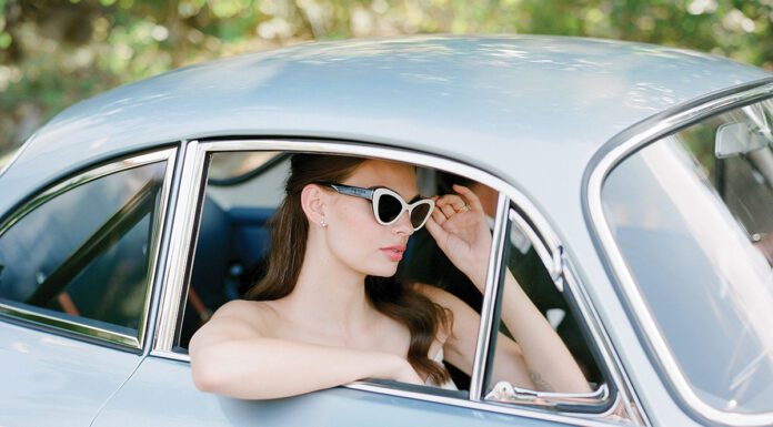 From This Day Forward: Timeless Wedding Gowns a bride sits in blue vintage porsche wearing prada sunglasses